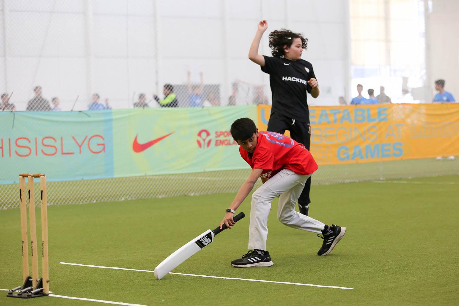 A young boy playing cricket on a field, swinging the bat with determination.