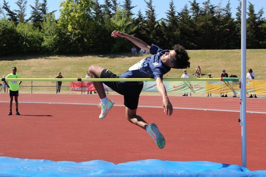 Young man leaping over high jump during competition.