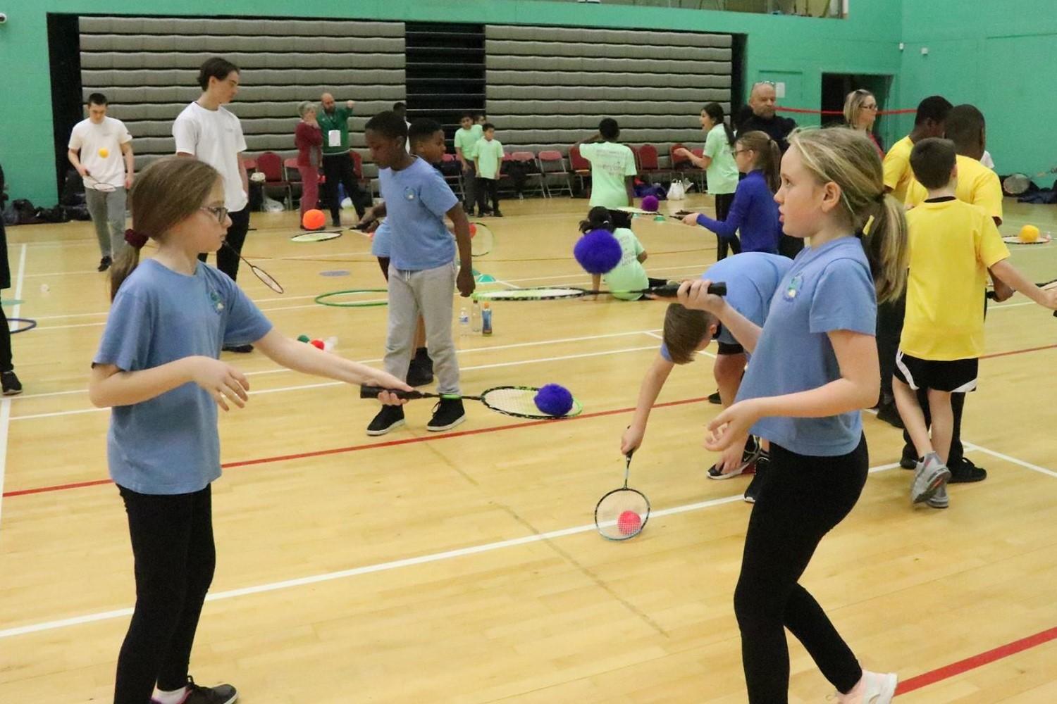 Children playing badminton in a gymnasium.