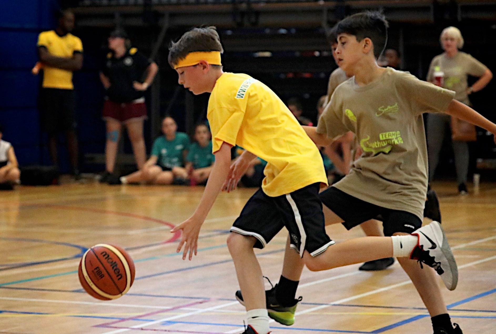 Two young boys playing basketball on a court.