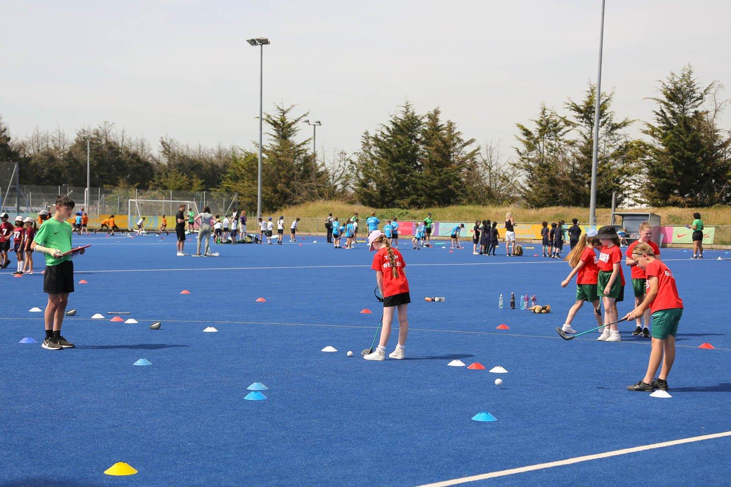 A group of children playing hockey on a blue field.