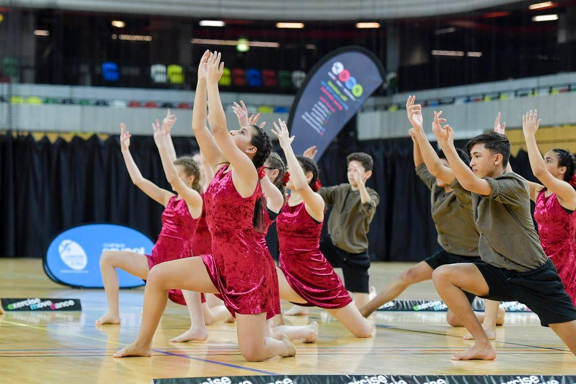 A dancer performing an elegant routine, with arms outstretched and a look of concentration on their face.