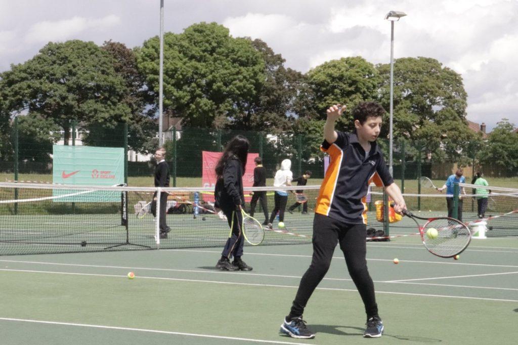 A group of people playing tennis on a court, enjoying a friendly match in the open air.