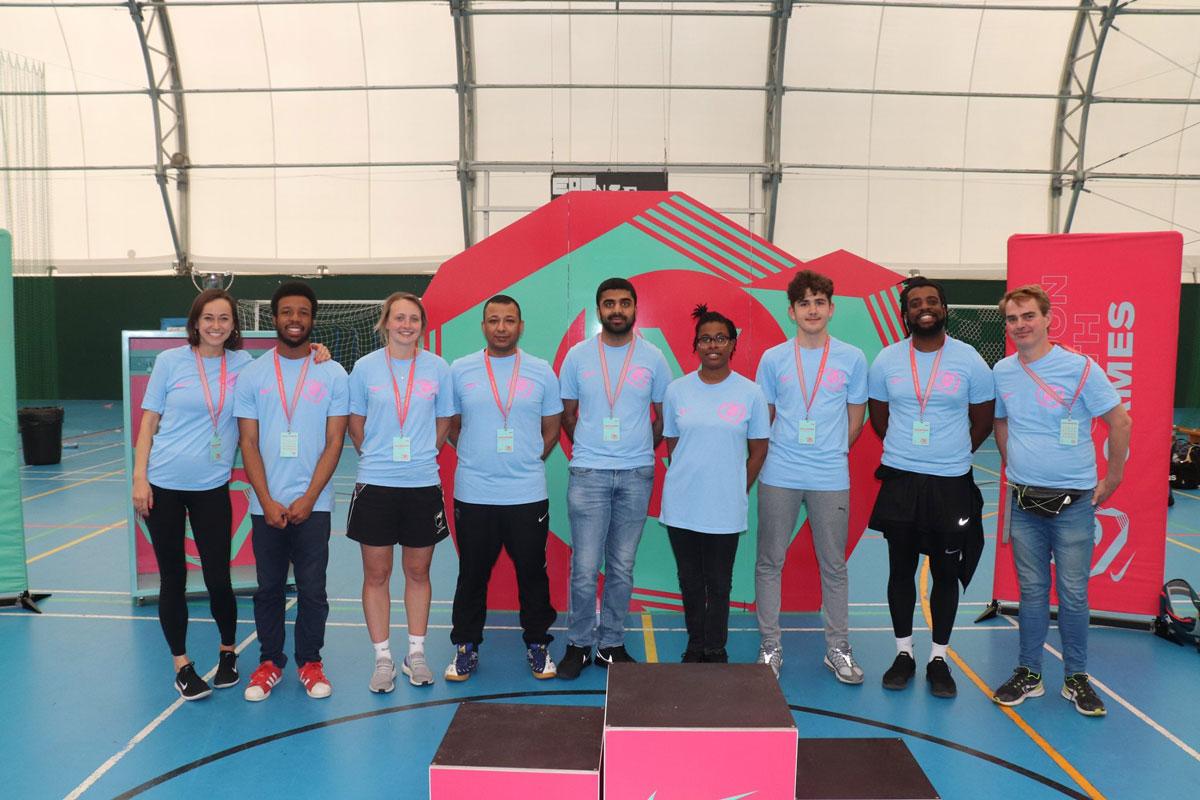 9 volunteers in blue tops stand and pose for photo