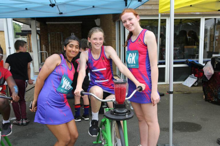 mixed ethnicity girls smile in front of smoothie bike