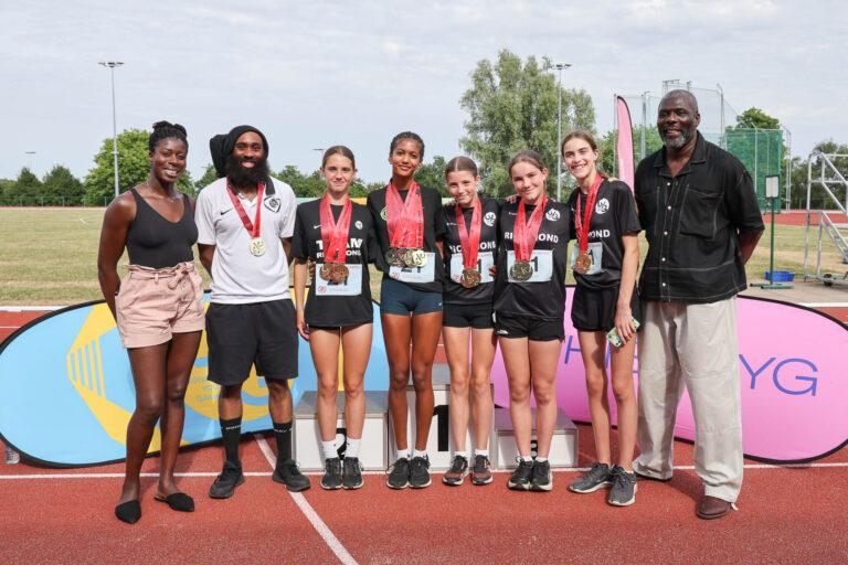 Group of athletes and coach stand for a photo