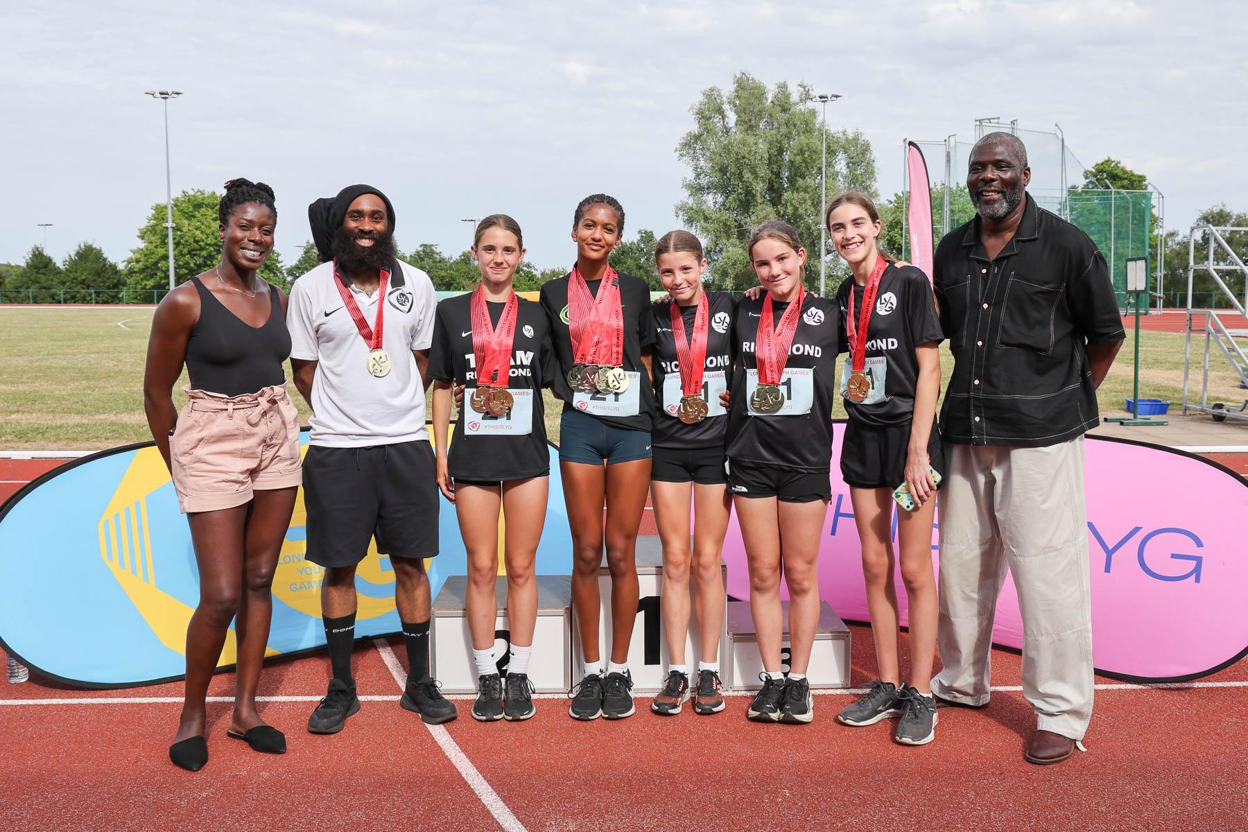 Group of athletes and coach stand for a photo