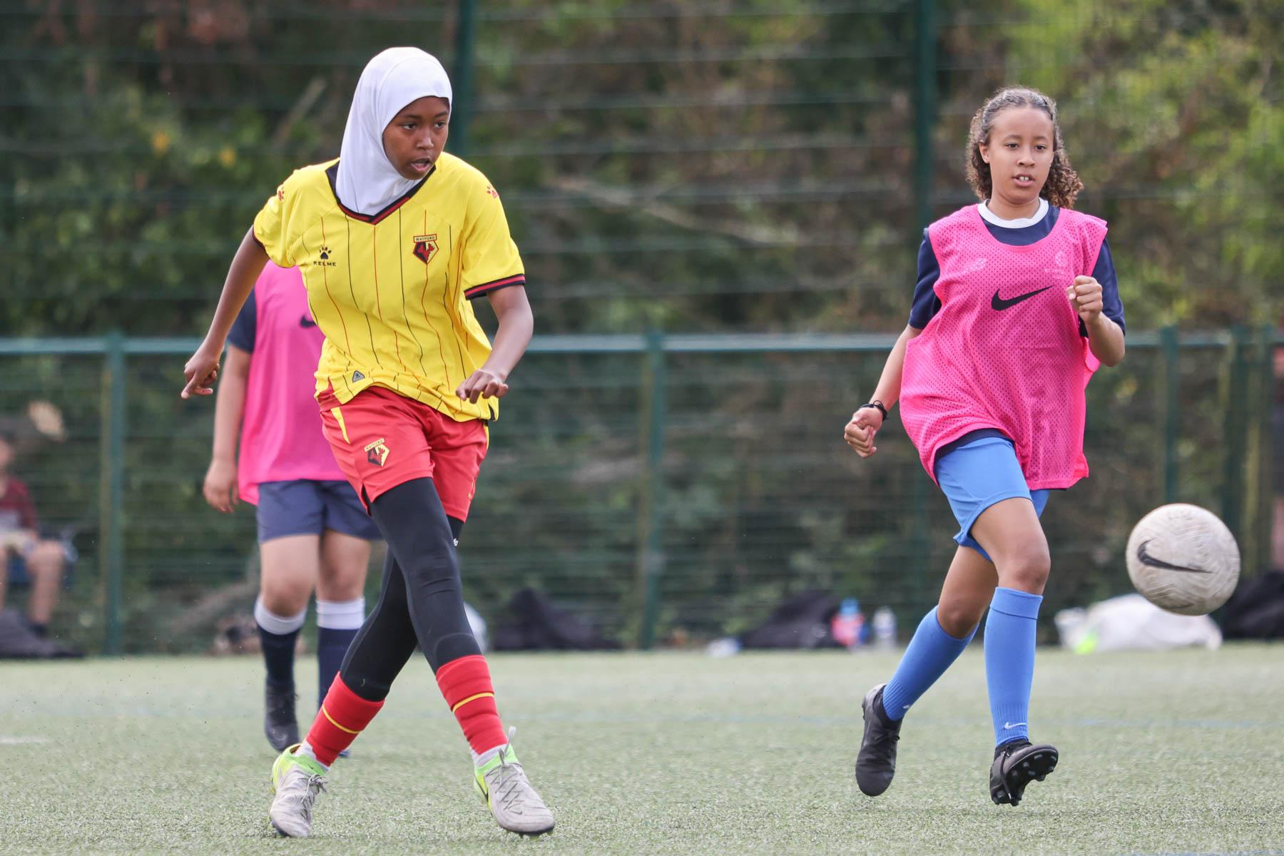 brown skin female with hijab plays football