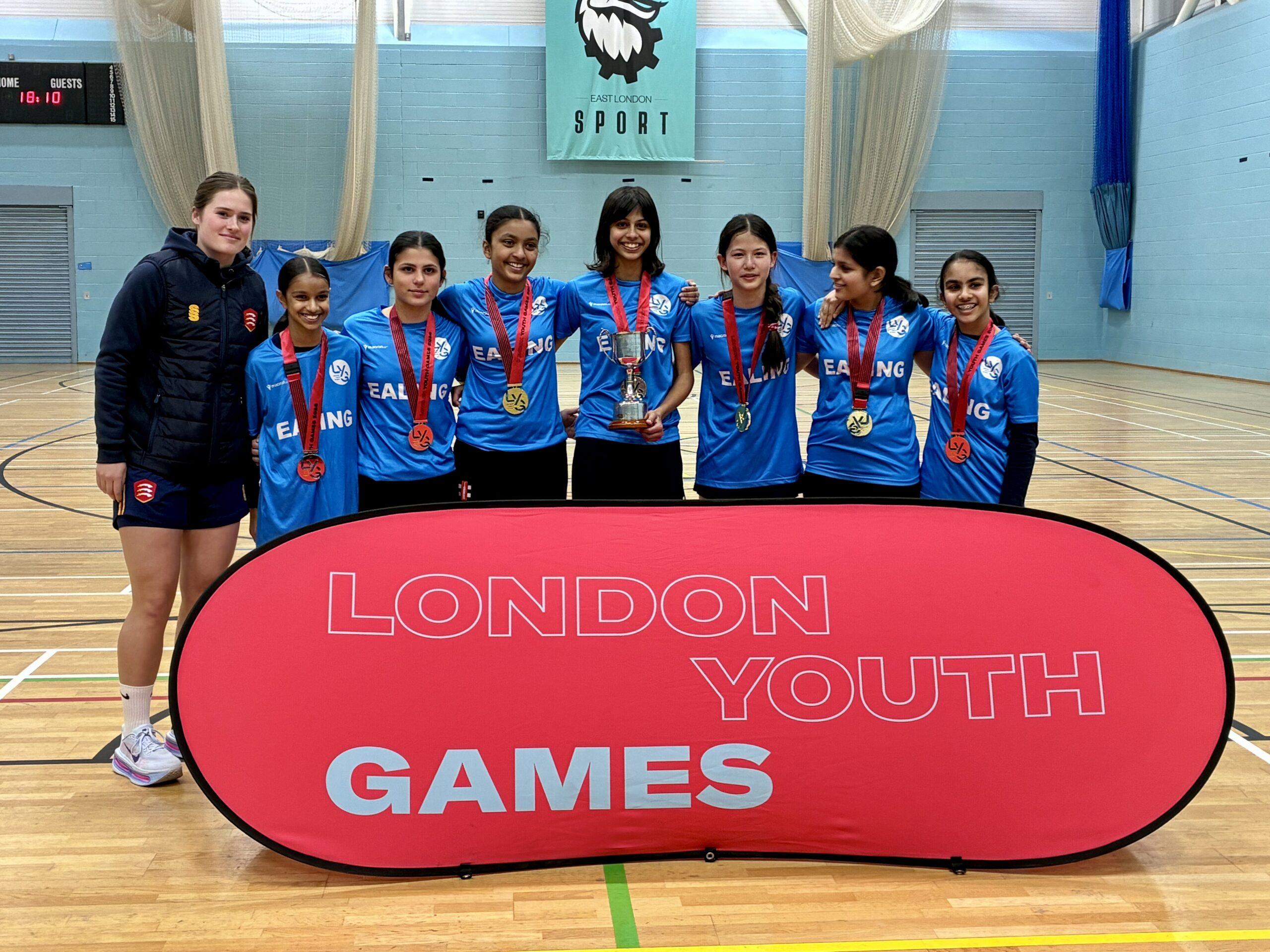 mixed ethnicity girls smile with medals and trophy with essex cricket player
