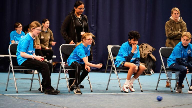 2 white girls, 1 brown boy play boccia