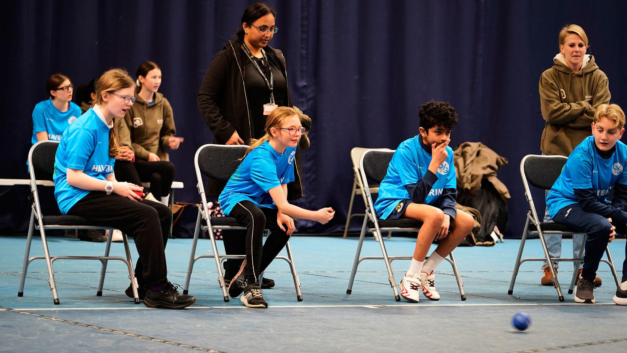 2 white girls, 1 brown boy play boccia