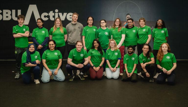 ethnically diverse coaches in green t shirts smile