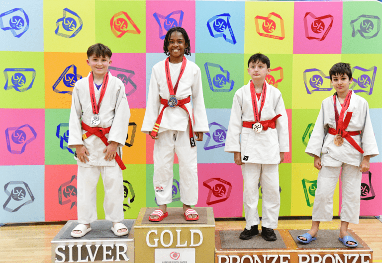 mixed ethnicity red belt judokas smile