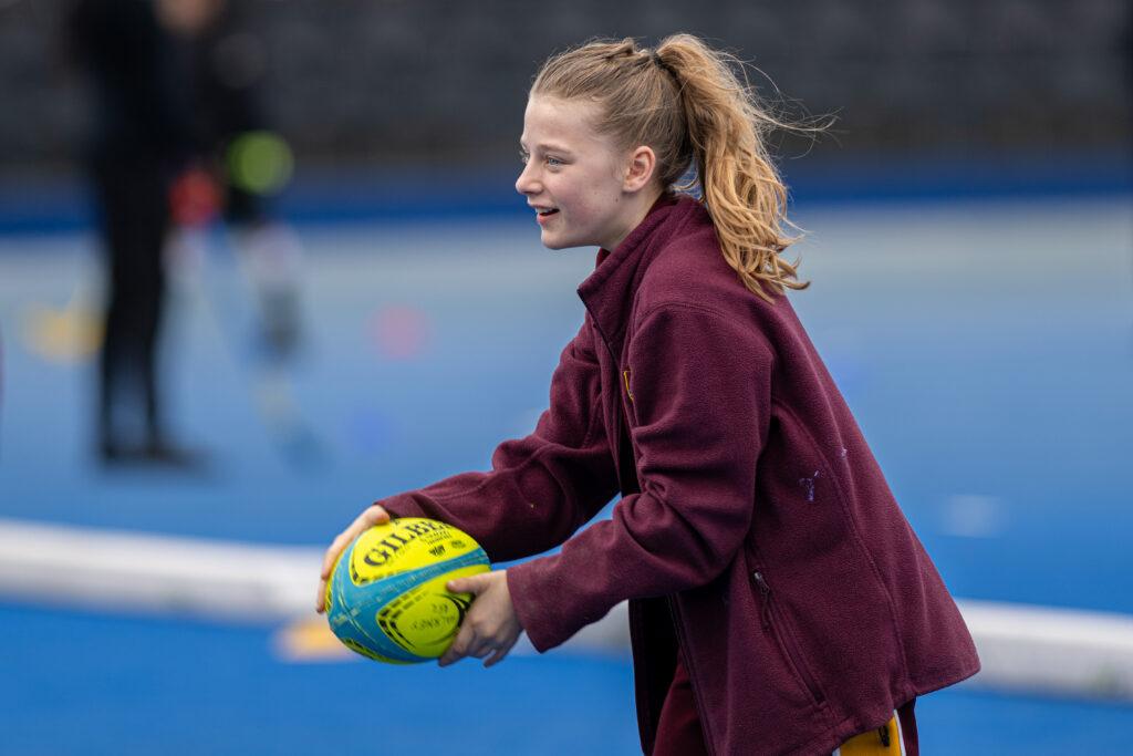 white female smiles and holds rugby ball